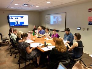 Image of WAVA Members around a conference table and joining on screen via WebEx